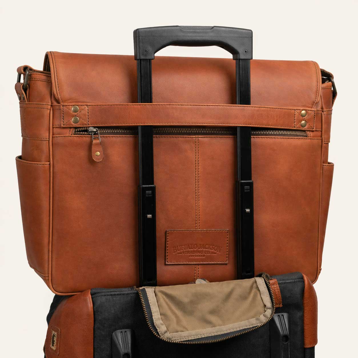 Brown leather briefcase with black handle and interior pocket on a beige background